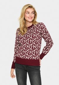 Pull en mailles bordeaux avec motif abstrait ivoire, col et poignets côtelés, coupe ajustée et texture douce. Convient pour un style décontracté.