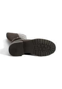 Bottine noire en cuir et tissu avec un bout pointu, fermeture éclair sur le côté, et semelle en caoutchouc texturé présentant un motif de crêtes et de formes.