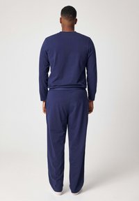 Donkerblauwe loungewear set met een top met lange mouwen en bijpassende broek in een ontspannen pasvorm, gemaakt van zachte stof voor comfort.