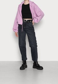 Sudadera cortada de lavanda con puños elásticos, combinada con unos vaqueros oscuros de cintura alta y botas de plataforma negras con detalles de hebilla.