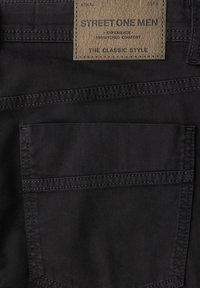 Pantaloni in denim nero con una finitura testurizzata, dotati di etichetta in pelle e di una tasca posteriore con cuciture rinforzate. Dettagli di design classici inclusi.