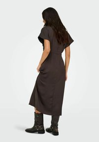 Ruda midi suknelė su trumpomis plazdančiomis rankovėmis, juosmeniu su diržu ir šoninėmis skiltelėmis. Sujungta su juodais ankle batus, puoštais sidabro detalėmis.