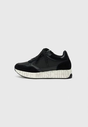 Zapatilla negra de cuero y ante con cordones negros y suela blanca con texto tenue "LOVE MOSCHINO", mostrada desde el lado exterior.