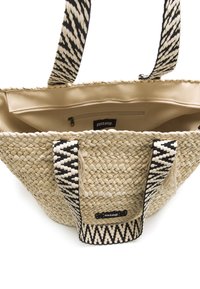 Bolsa de tote de paja tejida en color natural con asas con un patrón en blanco y negro; cuenta con un bolsillo interior con cremallera y detalles deshilachados.