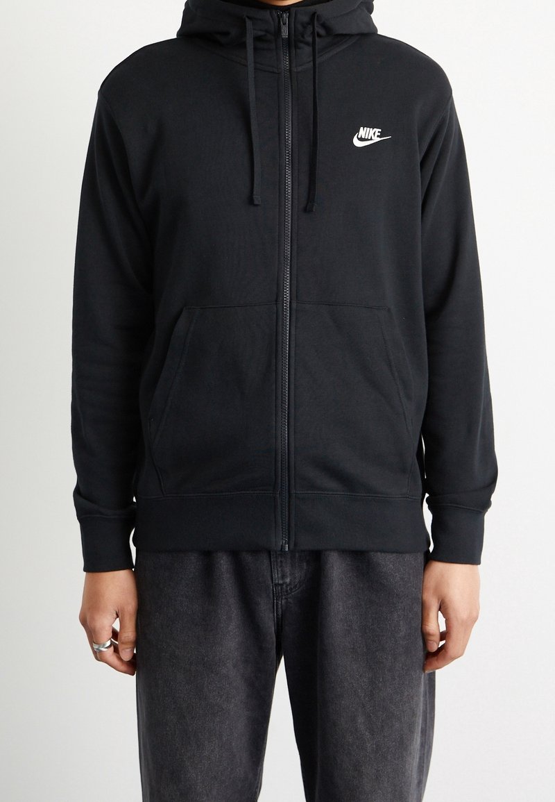 Svart zip-up hoodie i bomullsblandning. Har en framficka, dragsko i huvan och en liten vit Nike-logotyp på bröstet.