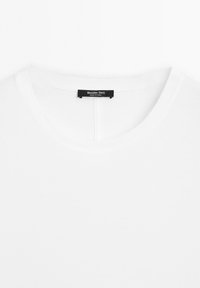 Bílá bavlněná tričko s kulatým výstřihem a černou etiketou uvnitř s textem "Massimo Dutti" a "Vyrobeno v Číně".