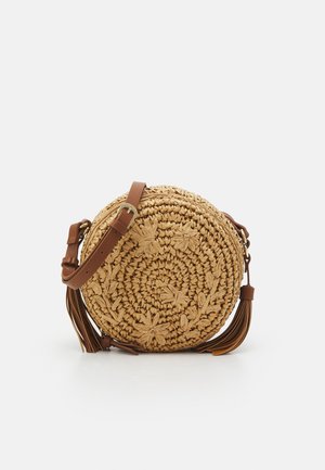 Sac rond en paille avec une sangle en cuir marron. Présente des détails floraux embossés et des pompons. Fabriqué à partir de fibres naturelles avec une finition texturée.