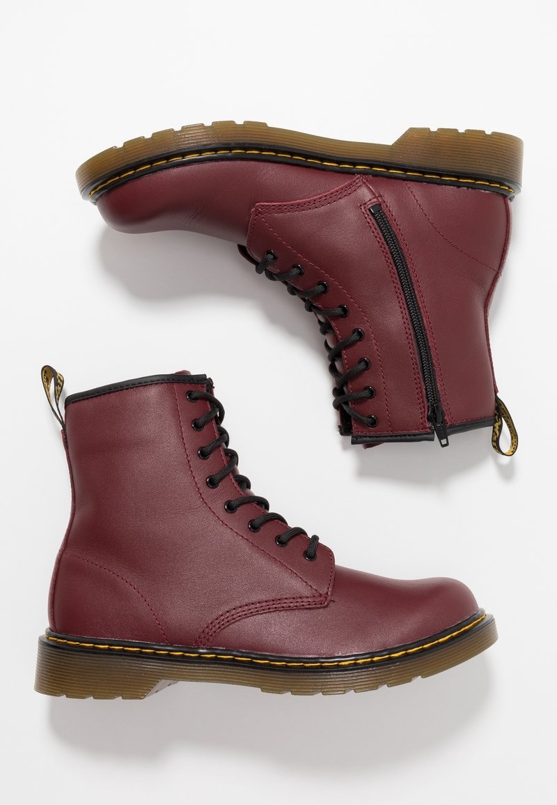 Bottes en cuir bordeaux à lacets avec fermeture éclair latérale, lacets noirs, couture jaune, et semelles en caoutchouc translucide marron, présentées vues de côté et de la semelle.