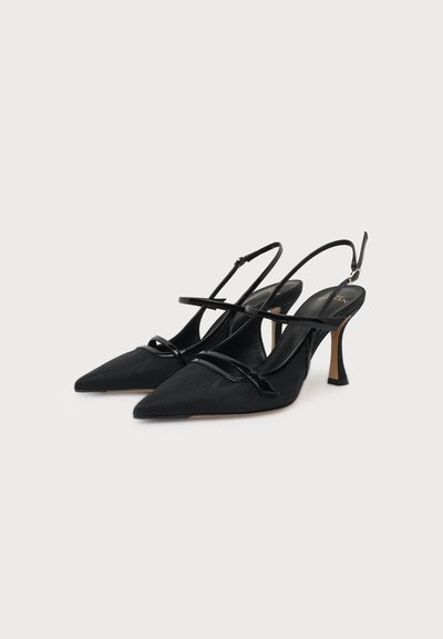 Ζευγάρι μαύρες γόβες slingback με μυτερή μύτη, λεπτά λουράκια και μεσαίου ύψους τακούνι στιλέτο, τοποθετημένες σε απλό φόντο.