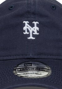 Tumši zilas krāsas regulējama cepure no auduma; ar baltu izšūtu "NY" logotipu; iekļauta apaļa birka ar "New Era" un "9TWENTY" uzrakstiem.