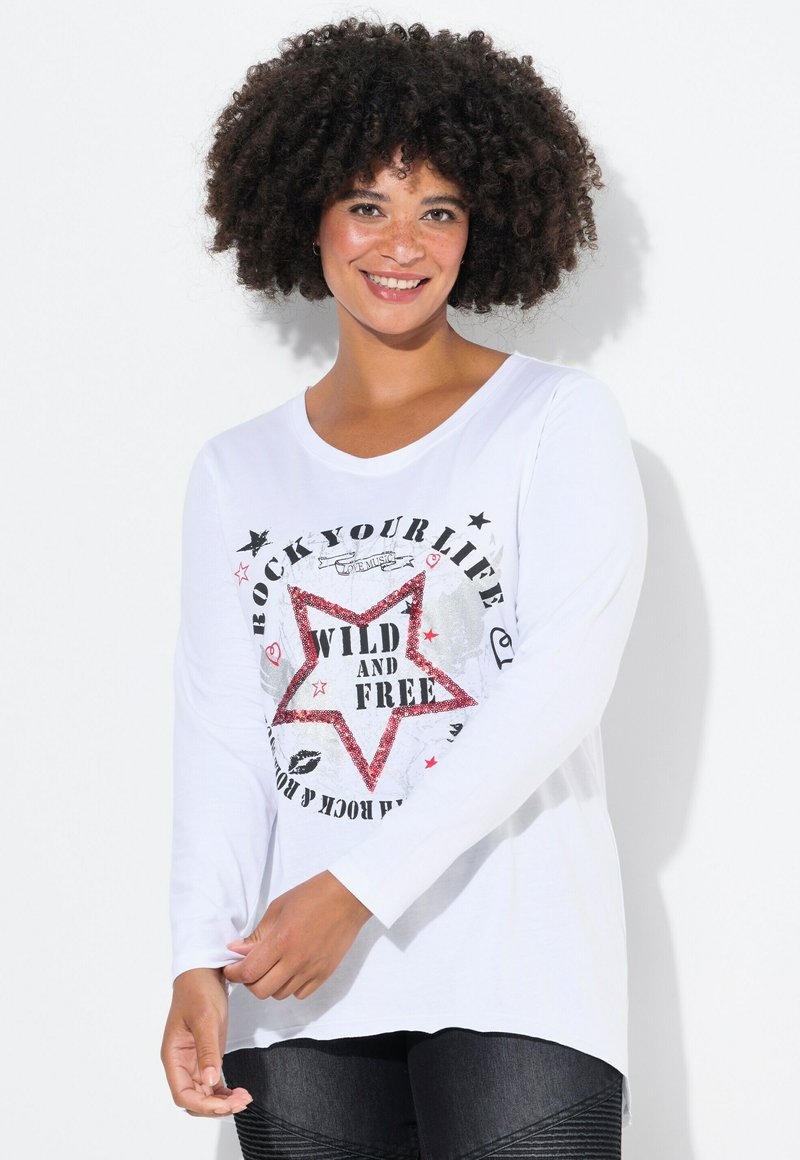 Valkoinen pitkähiha Shirt, jossa on graafinen printti, jossa on punainen tähti ja teksti "VILLI JA VAPAA" mustilla, hopeisilla ja vaaleanpunaisilla yksityiskohdilla.