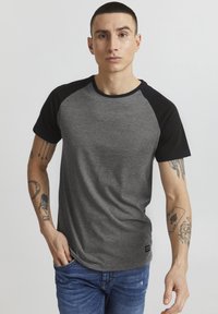 Camiseta raglán gris y negra hecha de tela suave, con cuello redondo y mangas cortas, con una sutil textura y detalle de logo en el dobladillo.