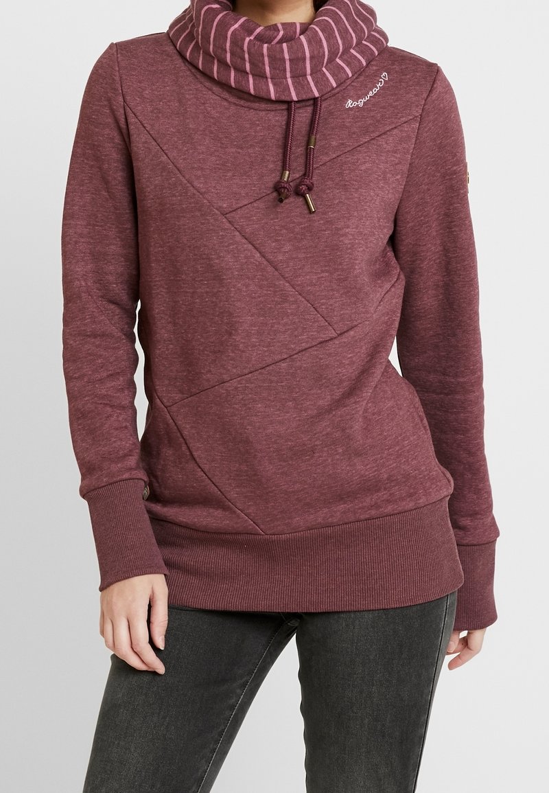Sudadera burdeos con cuello alto a rayas, tela texturada, diseño de costuras diagonales y puños y dobladillo acanalados. Presenta detalles con cordón.