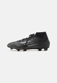 Black soccer cleat with a textured upper, gold accents, and lace-up design. Features a high ankle collar and molded plastic studs for grip.