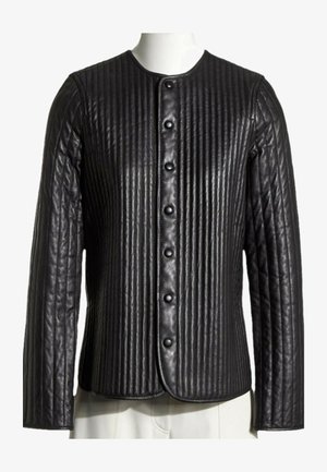Chaqueta de cuero negro con costuras acolchadas verticales y cuello redondo, con una fila frontal de botones a presión negros.