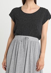 Czarny top z krótkim rękawem o fakturowanym wzorze, połączony z szaro-białą spódnicą w paski, wyposażoną w regulowany sznurek w talii.