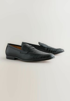 Black loafers made of textured leather, featuring a crocodile pattern and a smooth strap across the top. Low rectangular heel.