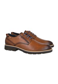 Zapatos de cuero marrón para hombre, tipo lace-up, con suelas negras y cordones azules, colocados en ángulo a la derecha sobre un fondo blanco.