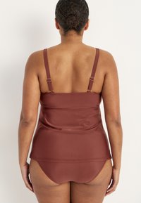 Rustfarvet tankini med justerbare stropper. Glat, strækbart stof former sig efter kroppen, med en løs pasform ved taljen og matchende briefs.