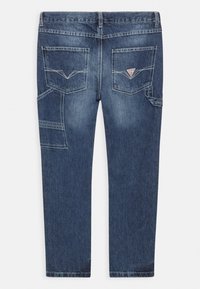 Tmavě modré džíny z denimu se střihem do rovna, vybavené dvěma zadními kapsami, boční kapsou a kontrastním prošitím. Na jedné kapse je logo.