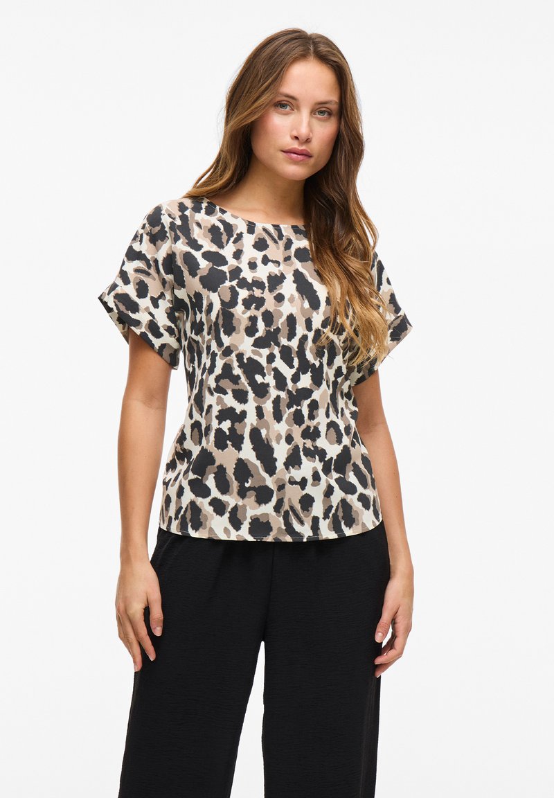 Lühikeste varrukatega leopardimustriga topp beeži, musta ja pruuni toonides. Lahtine lõige ja ümar kaelus. Sile kangas, millel on õrn sära.