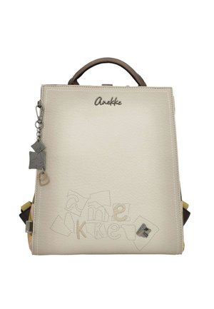 Zaino Anekke color crema con logo ricamato, manico marrone e ciondolo decorativo in metallo sul lato.