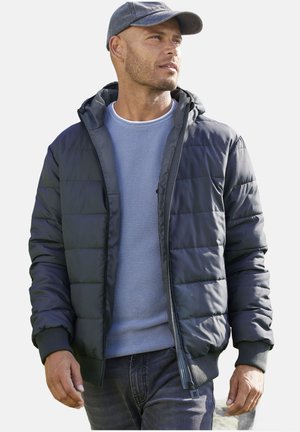 Gevoerde jas in donkergrijs, met een capuchon, geribde manchetten en een ritsluiting. Draagstijl over een lichtblauwe trui en in combinatie met jeans.