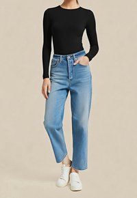 Černý top s dlouhým rukávem ve spojení s džíny světle modré barvy s vysokým pasem, rovnými nohavicemi a neupraveným spodním lemem. Nosit s bílými teniskami.