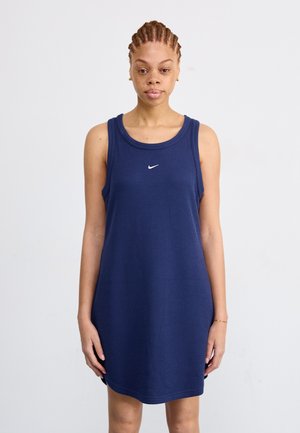 Robe débardeur côtelée bleu marine avec un col rond, des fentes latérales et un petit logo Nike blanc sur la poitrine. Tissu en mélange de coton.