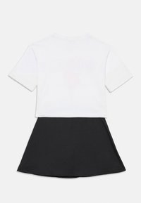 Cropped top bianco con maniche corte, abbinato a una gonna nera a effetto svasato. Tessuto liscio, linee pulite e senza motivi o accenti visibili.