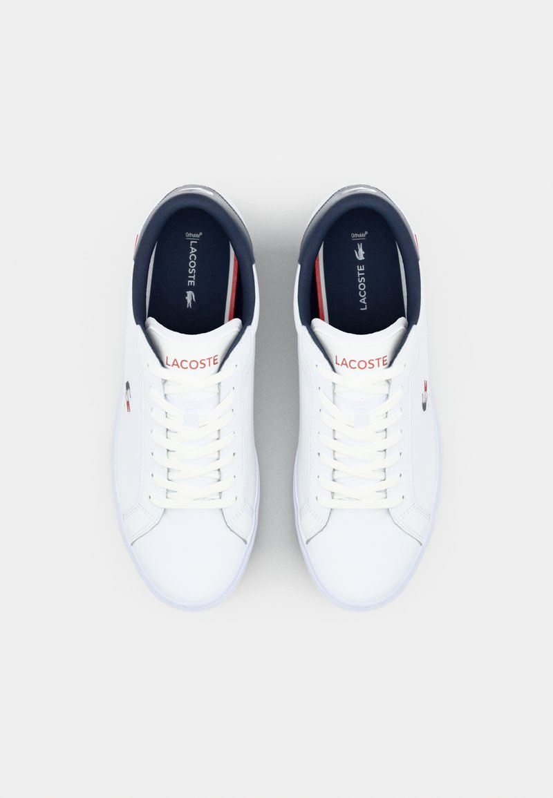 Białe skórzane sneakersy o gładkiej fakturze, granatowe akcenty na kołnierzu oraz czerwone logo z boku. W zestawie sznurowadła i wyściełany język.