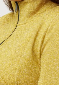 Sudadera amarilla con cremallera que presenta un patrón texturizado y entrelazado. Cuello alto y detalle de cremallera en contraste. Tejido de punto suave.