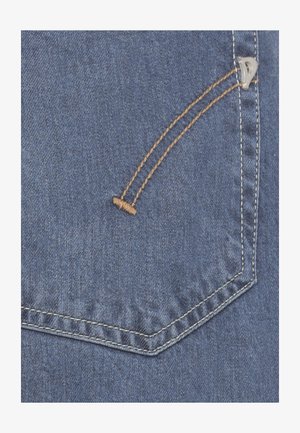 Close-up van blauwe denim stof met een geïntegreerde achterzak, voorzien van dubbele oranje en witte stiknaden en een kleine metalen klinknagel.