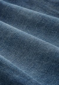 Dunkelblauer Denim-Stoff mit glatter Textur, der eine sichtbare Köperbindung und subtile Farbvariationen auf der Oberfläche aufweist.