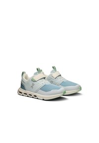 Light blue athletic shoes with mesh and synthetic upper, white midsole, green accents, and patterned sole. Features a hook-and-loop strap.