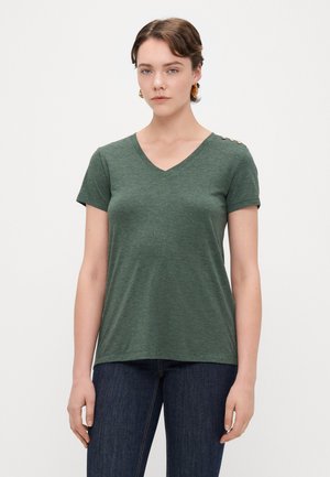 Žalias v-kaklo marškinėlis iš minkštos medžiagos su trumpomis rankovėmis ir trimis dekoratyvinėmis mygtukais kairėje pečių pusėje. Tiesus apvadas, laisvalaikio stiliaus.