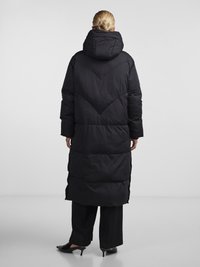 Long black puffer coat with a hood, featuring a chevron pattern on the back, quilted texture, and a mid-calf length.
