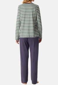 Långärmad randig topp i dämpad grön och vit, ihop med mörklila byxor. Mjuk textil, avslappnad passform och enkel design.
