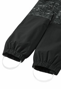 Czarne spodnie outdoorowe z elastycznymi mankietami, z błyszczącą, wzorzystą górną częścią. Zawierają białe sznurki do regulacji.