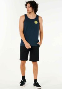 Marineblå tanktop med et cirkulært gult grafik, parret med sorte shorts. Stoffet ser glat ud, og designet er enkelt og moderne.