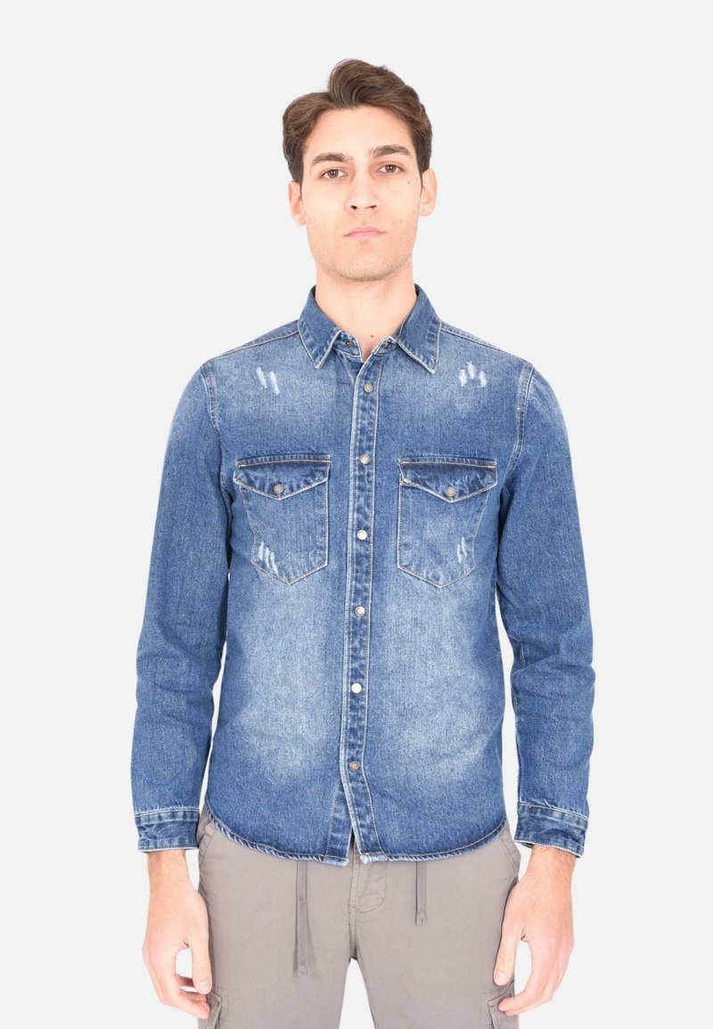 Camicia di jeans azzurro chiaro con finitura consumata, dotata di doppi taschini sul petto, chiusura con bottoni, maniche lunghe e orlo curvo.
