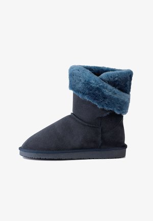 Tummansininen nilkkuri, joka on valmistettu mokasta ja jossa on pehmeä, karvavuorattu kaulus. Ominaisuuksia ovat pyöreä kärki ja litteä kumipohja mukavuutta varten.