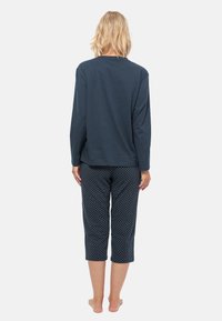 Marineblauwe langemouwen top gecombineerd met cropped broek met stippen. Zachte stof, relaxte pasvorm en lichte textuur. De broek heeft een losse silhouet.