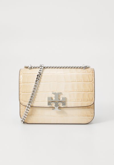 Beige leren handtas met krokodillenreliëf, een zilveren chain strap en een opvallend zilveren logo op de voorkant. Rechthoekige vorm.