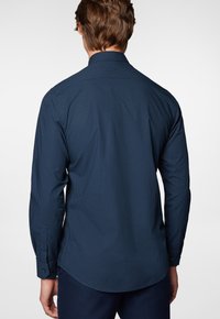 Granatowa koszula z długim rękawem z małym wzorem geometrycznym, z guzikami przy mankietach i klasycznym kołnierzykiem, wykonana z gładkiego materiału.