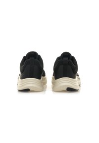 Scarpe da ginnastica nere con superiore in rete traspirante, colletto imbottito e suola in gomma beige a contrasto. Presenta una linguetta sul tallone.