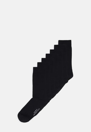 Schwarze Baumwollsocken, die in einer diagonalen Linie angeordnet sind, mit einem gerippten Design und einer glatten Textur, wobei an einer Socke das Größen- und Komfortlabel angebracht ist.