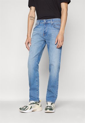 Jeanși din denim de culoare albastru deschis, cu croială dreaptă, design cu cinci buzunare și decolorare subtilă. Purtați cu adidași în culori neutre și un tricou negru.