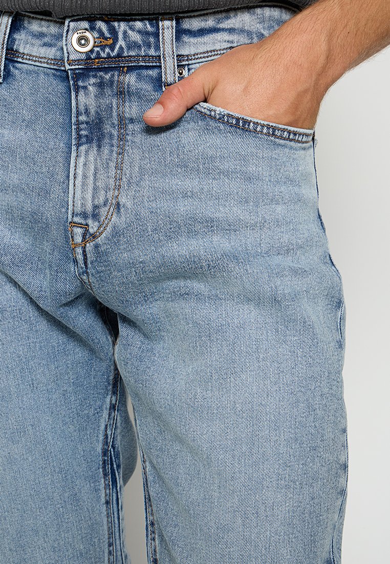 Hellblaue Denim-Jeans mit glatter Textur, klassischem Schnitt, sichtbaren Nähten und einer Vordertasche.