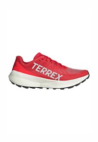 Scarpa sportiva rossa con tomaia in rete, logo "TERREX" bianco, suola intermedia spessa e suola in gomma nera con battistrada testurizzato per la trazione.